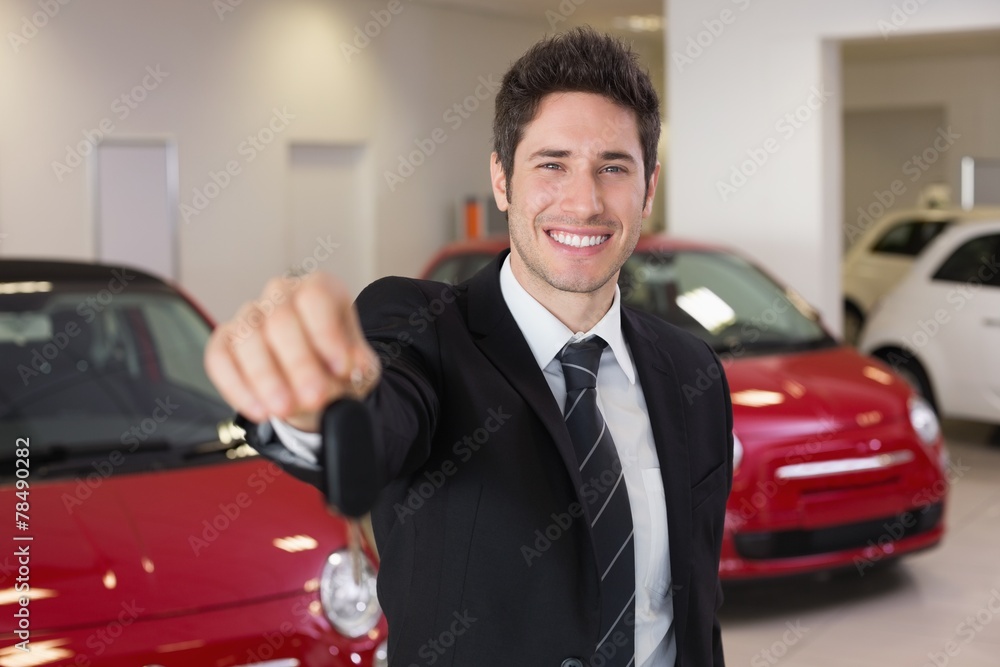 Salesman standing while offering car keys Salesman standing while offering car keys