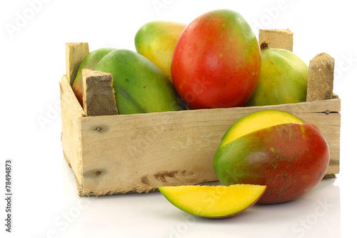 mango fruit and a cut one in a wooden box on a white background