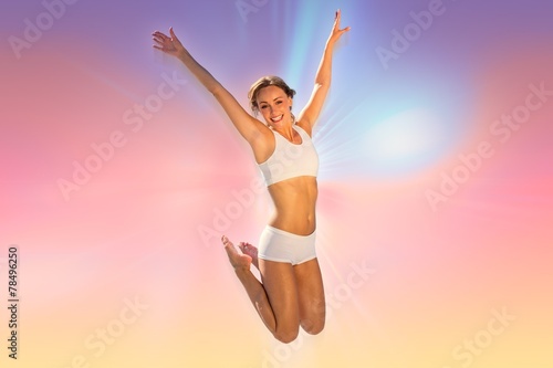 Composite image of gorgeous fit blonde jumping with arms out