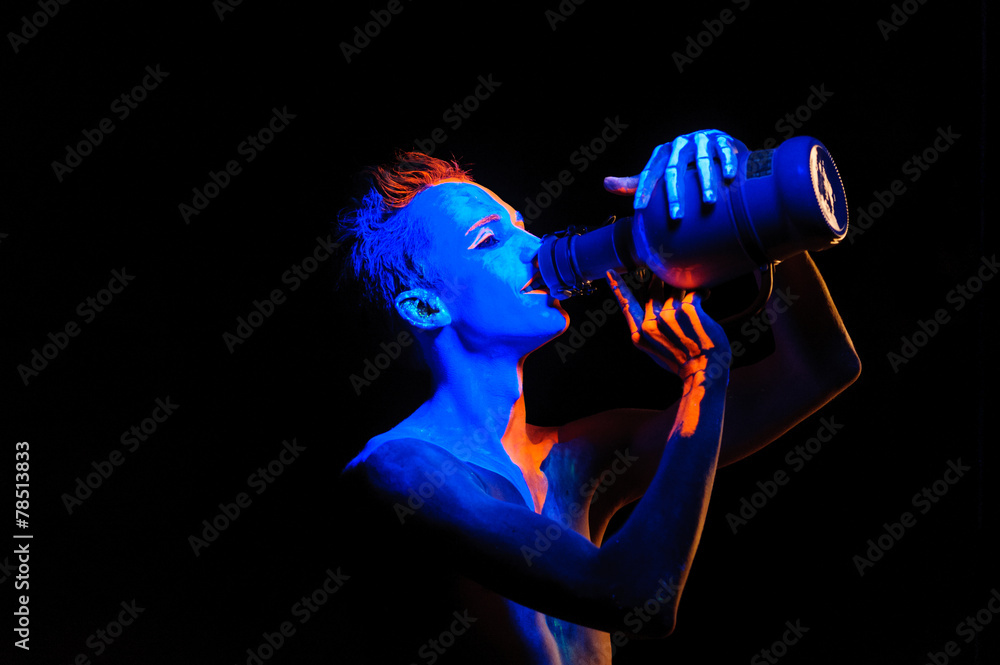 Man covered with fluorescent paint playing in the dark
