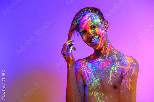 Man covered with fluorescent paint on color background