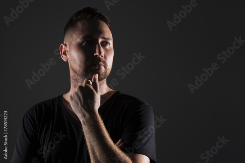 Man posing with dark background and hard lighting