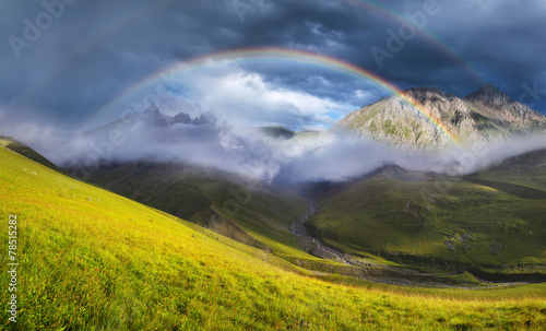 Rainbow in mountain valley during sunset