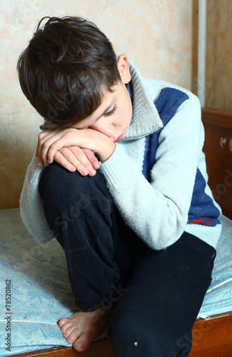 preteen handsome boy sit on the bed sad and depressed