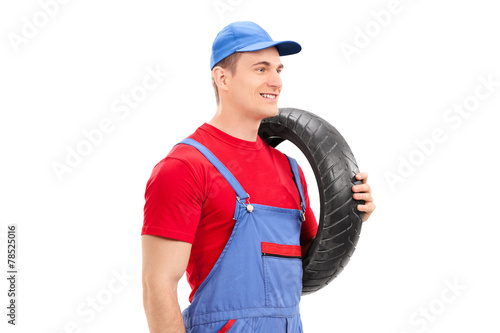 Mechanic carrying a tire and walking