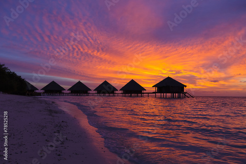 Sunset in the Maldives with a view of the lagoon and bungalows