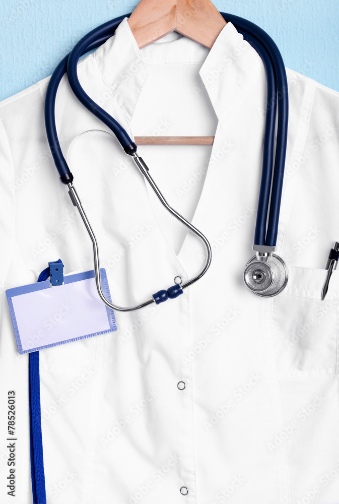 Doctor coat with stethoscope on hanger on blue background Doctor coat with stethoscope on hanger on blue background