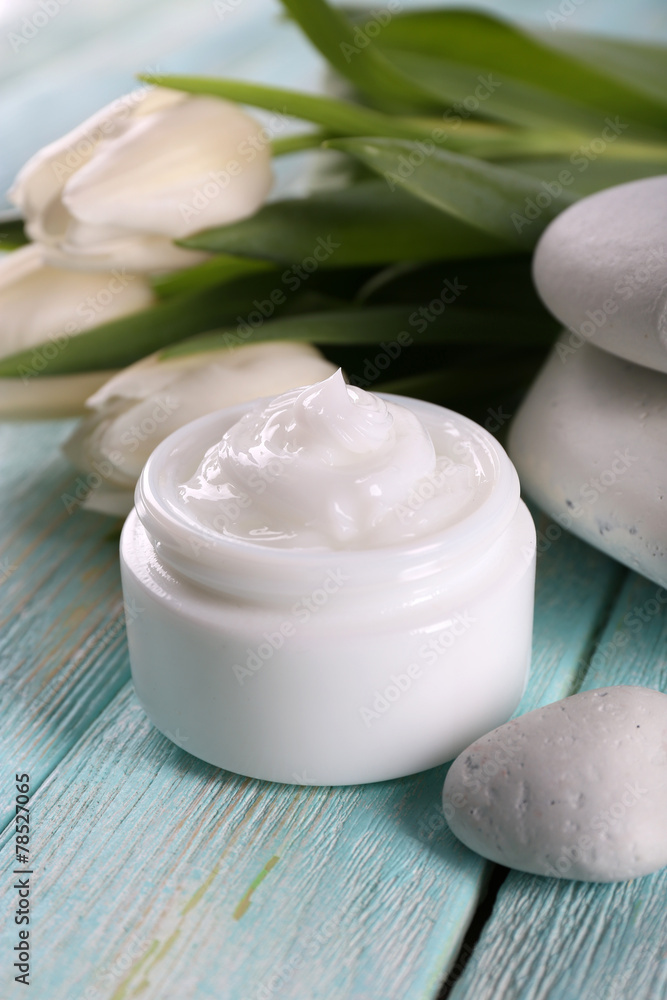 Cosmetic cream with flowers and spa stones on wooden background Cosmetic cream with flowers and spa stones on wooden background