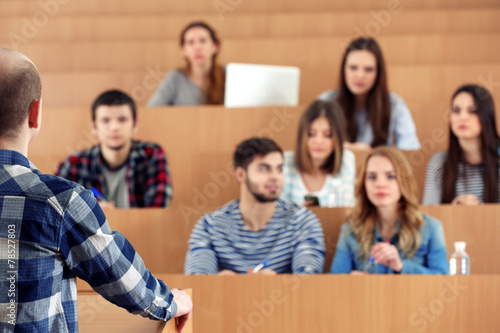 Group of students sitting in classroom and listening teacher