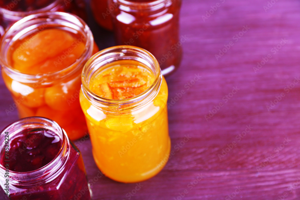 Homemade jars of fruits jam on color wooden background Homemade jars of fruits jam on color wooden background