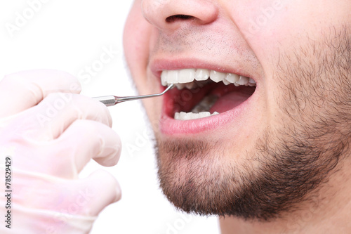 Examine of young man by dentist isolated on white background