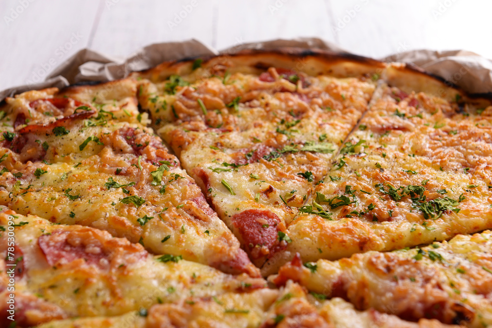 Tasty pizza on paper on wooden background Tasty pizza on paper on wooden background
