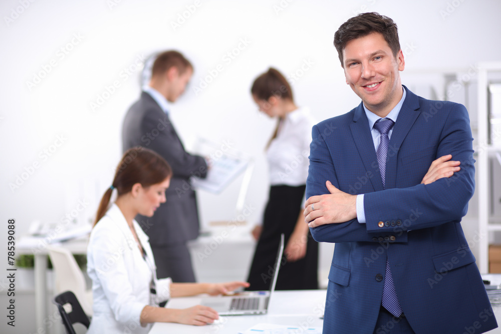 Successful business man standing with his staff in office Successful business man standing with his staff in office