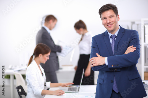 Successful business man standing with his staff in office