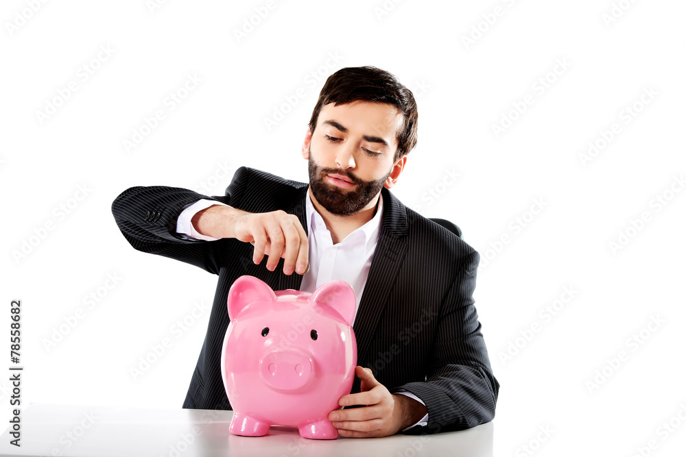 Businessman putting a coin to piggybank. Businessman putting a coin to piggybank.