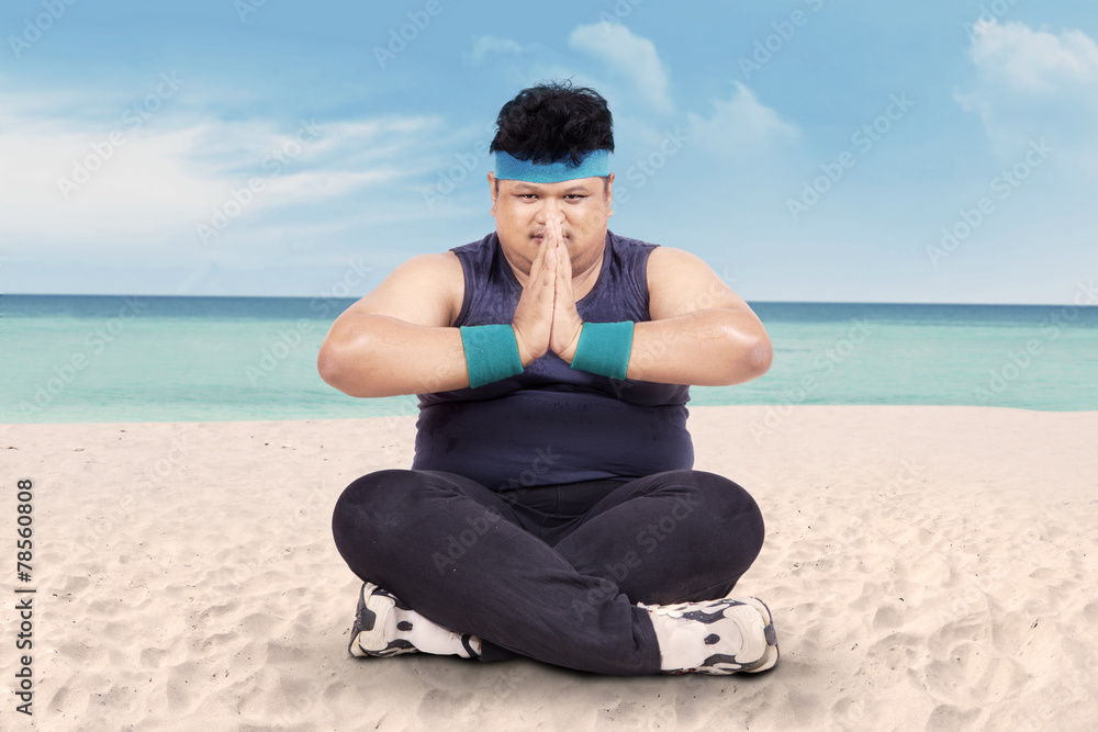Overweight man doing yoga on beach 1 Overweight man doing yoga on beach 1