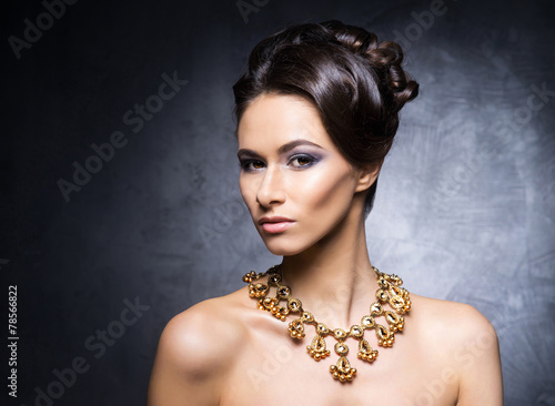 Young, beautiful and rich woman in jewels of gold