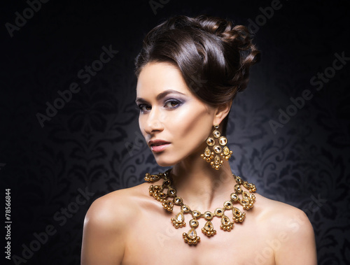 Young, beautiful and rich woman in jewels of gold and stones