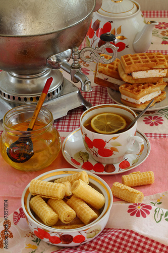 Tea from a samovar, with a lemon, honey, cakes and wafers