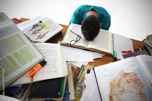 Medical student sit at the desk, study medical literature, take an exam. Stressed and tired young male photo