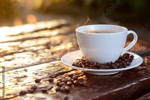 Hot coffee in the cup on old wood table with coffee beans