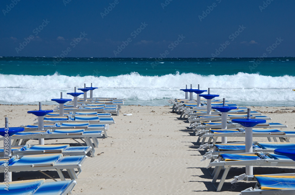 Row of blue deck chairs on a beach