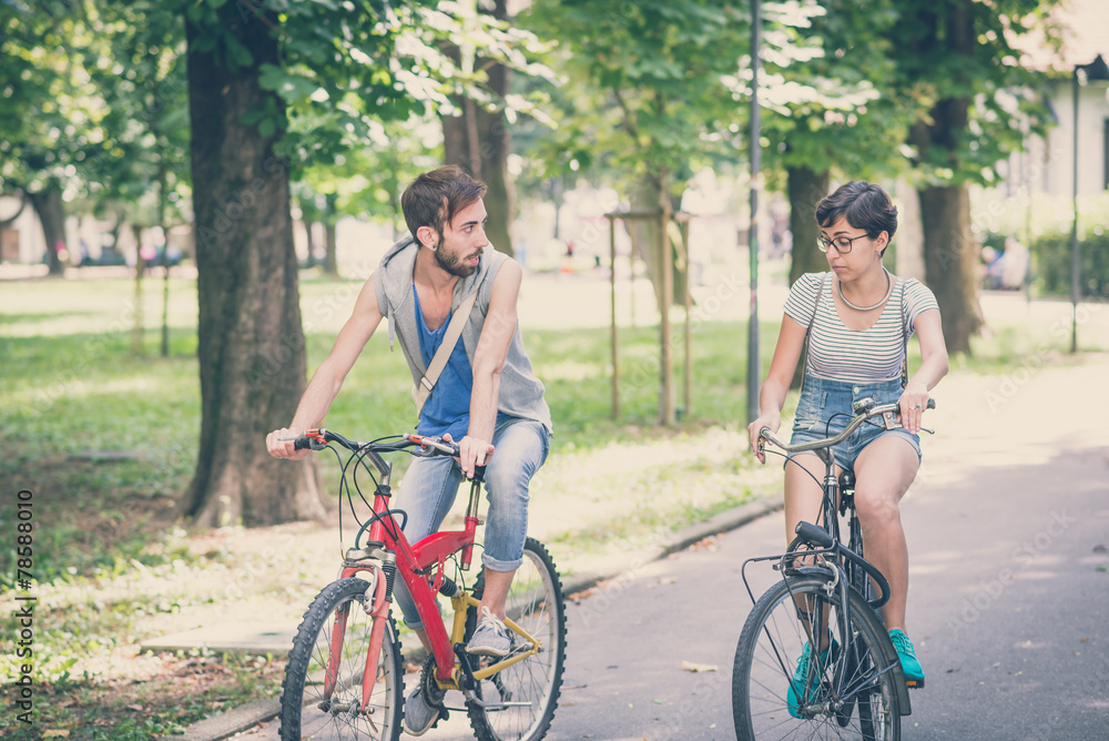 Obraz premium couple of friends young man and woman riding bike