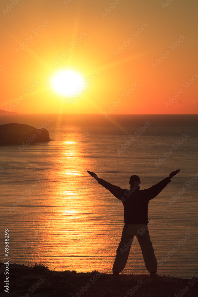 Man doing yoga on the beach at sunset