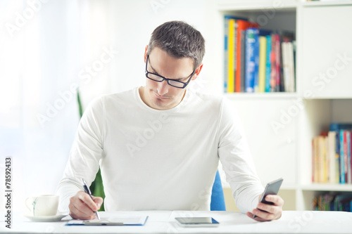 Young man working at home using mobile phone