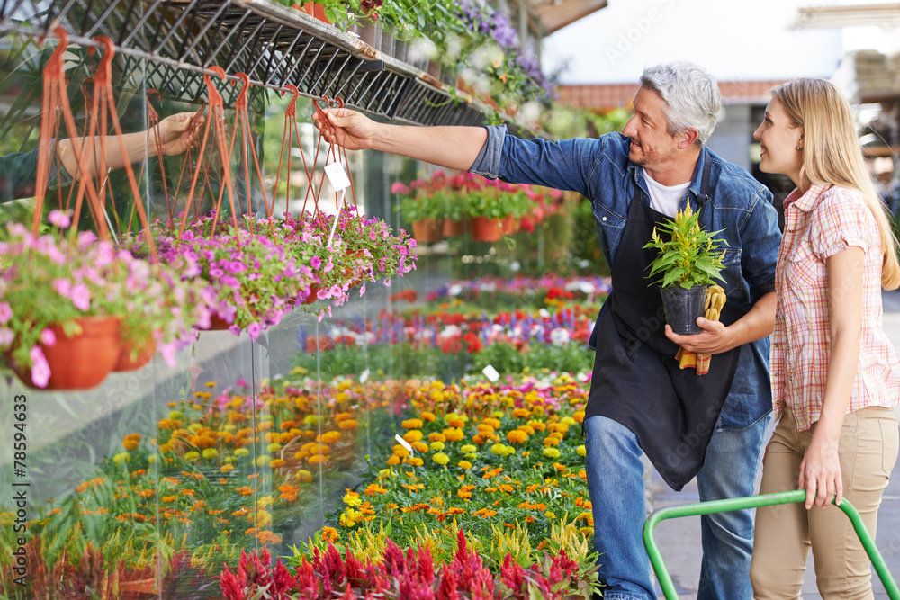 Gärtner vor Blumenladen hilft Kundin