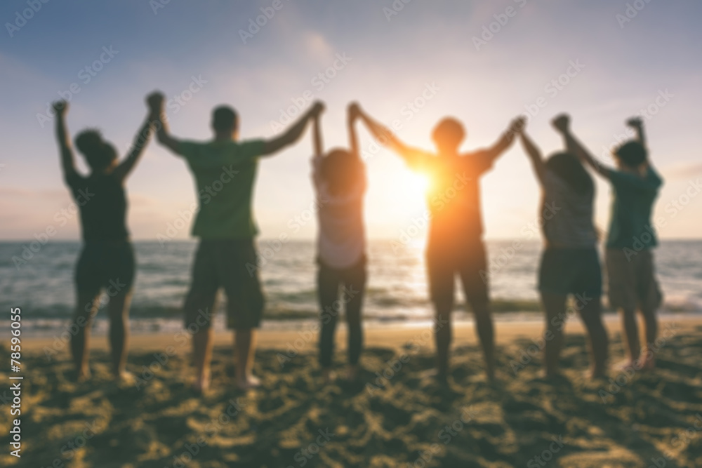 Group of people with raised arms at seaside, blurred background Group of people with raised arms at seaside, blurred background