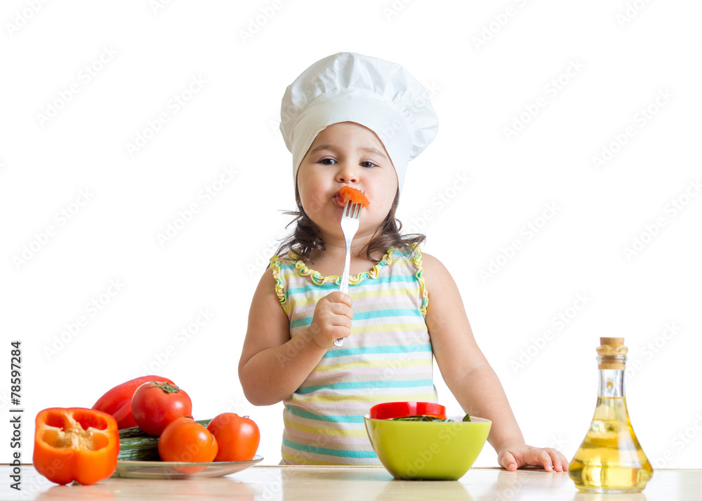kid girl in cook hat eating vegetables kid girl in cook hat eating vegetables
