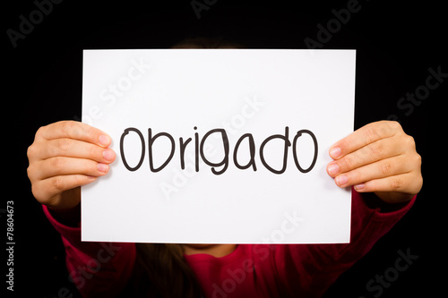 Child holding sign with Portuguese word Obrigado - Thank You