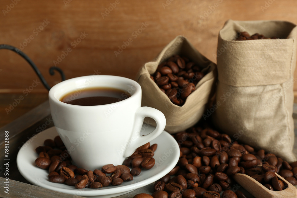 Fototapeta premium Cup of coffee with beans on tray and rustic wooden background