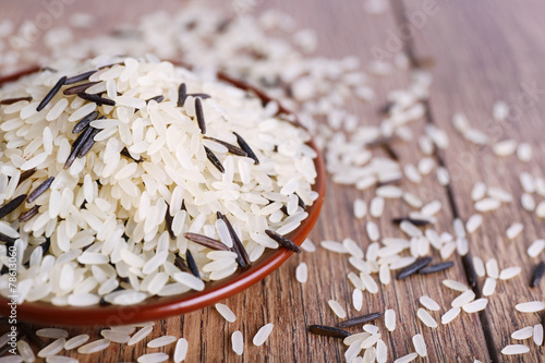 Grain of rice on plate on wooden background