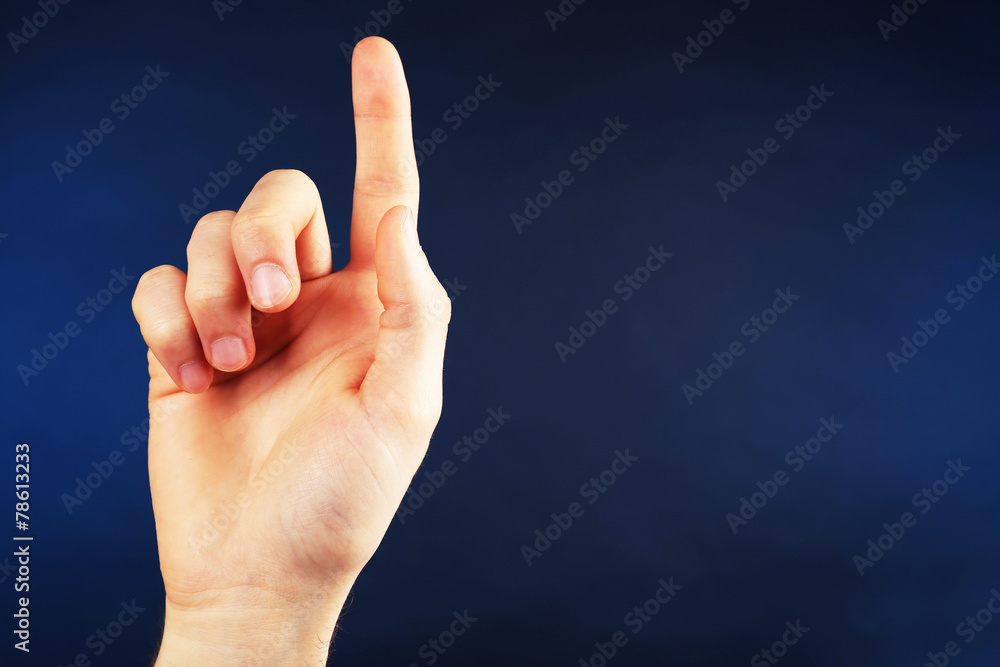 Male hand pointing up on dark blue background Male hand pointing up on dark blue background