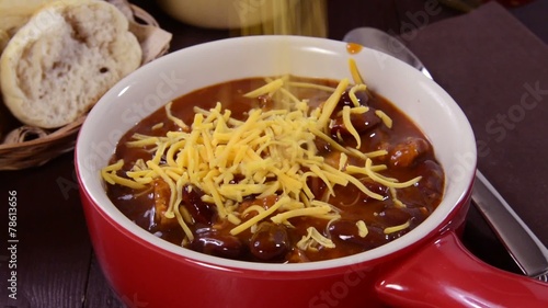 Sprinkling cheddar cheese on a bowl of chili