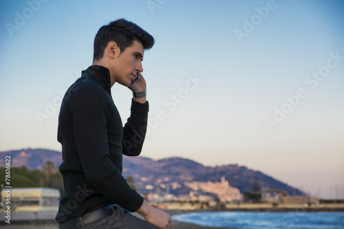 Young man at the seaside talking on cell phone