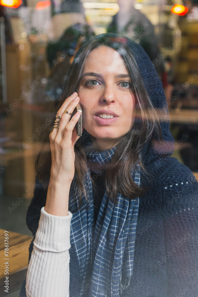 Beautiful girl talking on phone behind a window Beautiful girl talking on phone behind a window
