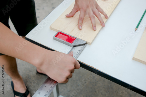 Carpenter working on a hand measuring wood board with ruler