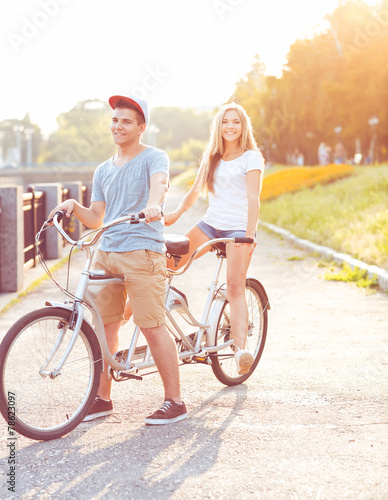 Happy couple riding a bicycle in the park outdoors