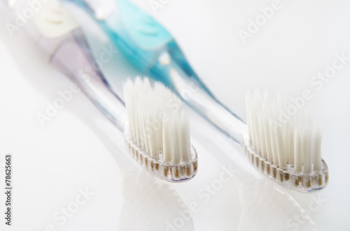 white and turquoise toothbrushes on white table