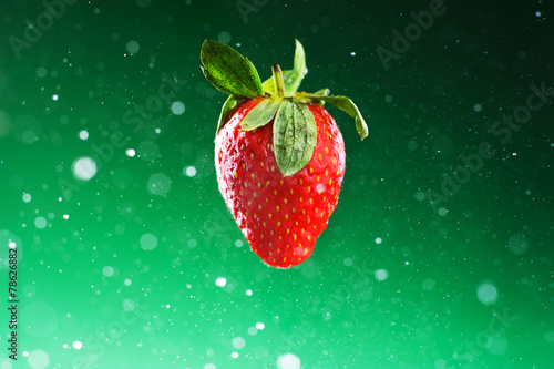 Strawberry on a green background with drops of water