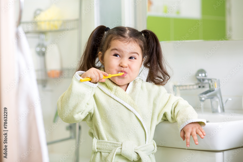 Smiling little girl brushing teeth in bathroom Smiling little girl brushing teeth in bathroom