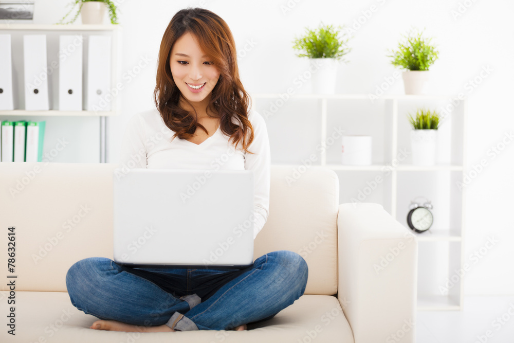 smiling Young woman sitting on the sofa with laptop smiling Young woman sitting on the sofa with laptop