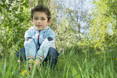 Spring sitting on the grass and dandelions cute boy.