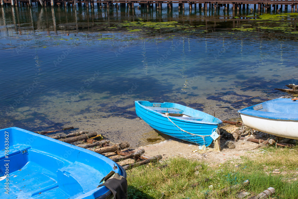 Blue boats on the beach and wooden pier
