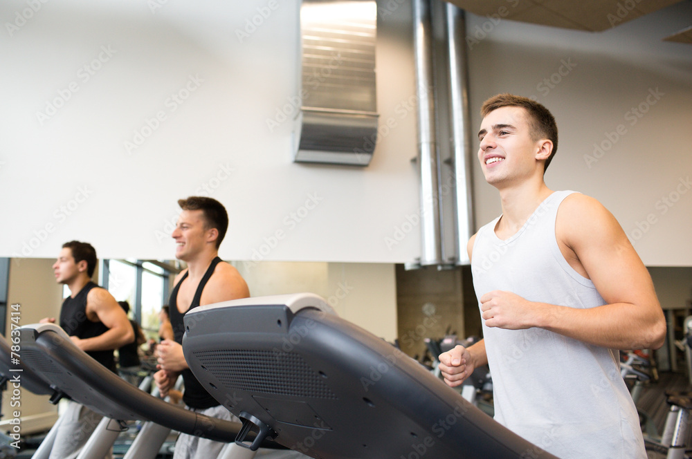 smiling men exercising on treadmill in gym smiling men exercising on treadmill in gym
