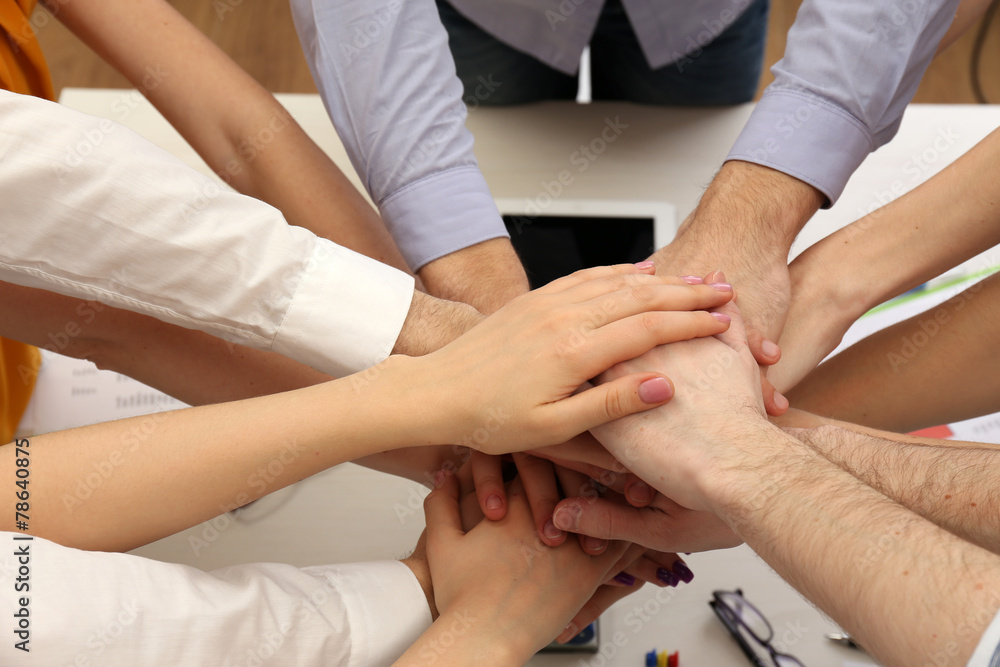 United hands of business team on workspace background top view United hands of business team on workspace background top view