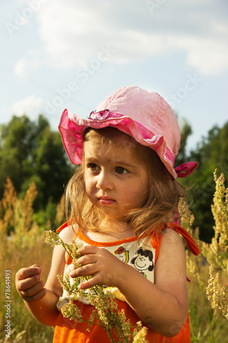 Cute little girl playing in meadow at sunset